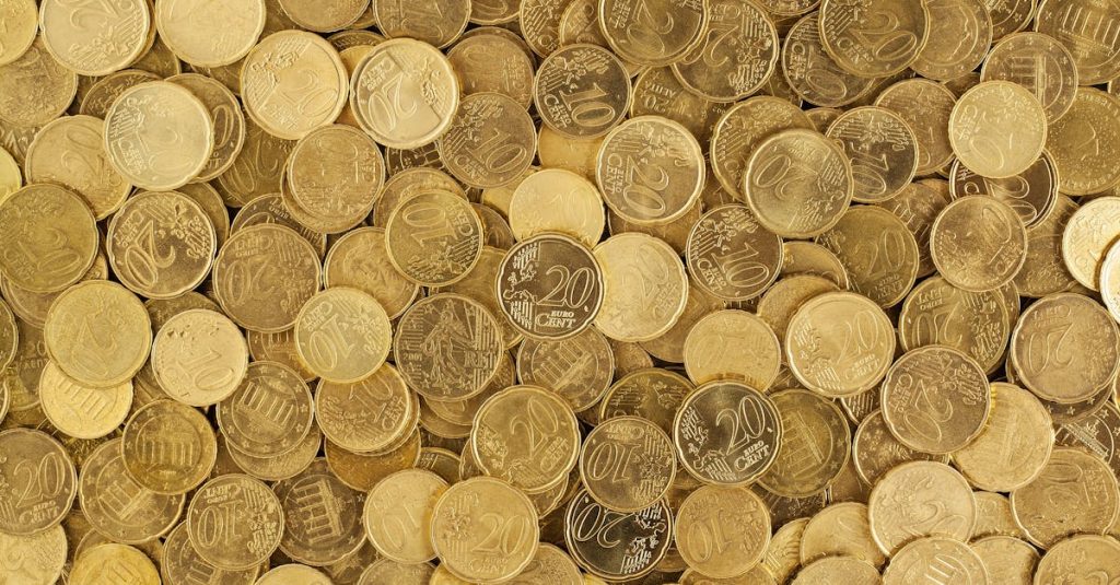 A close-up shot of Euro coins scattered in a pile, showcasing a rich golden texture.