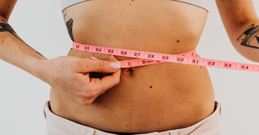 A woman measuring her waist with a pink measuring tape, focusing on fitness and health.